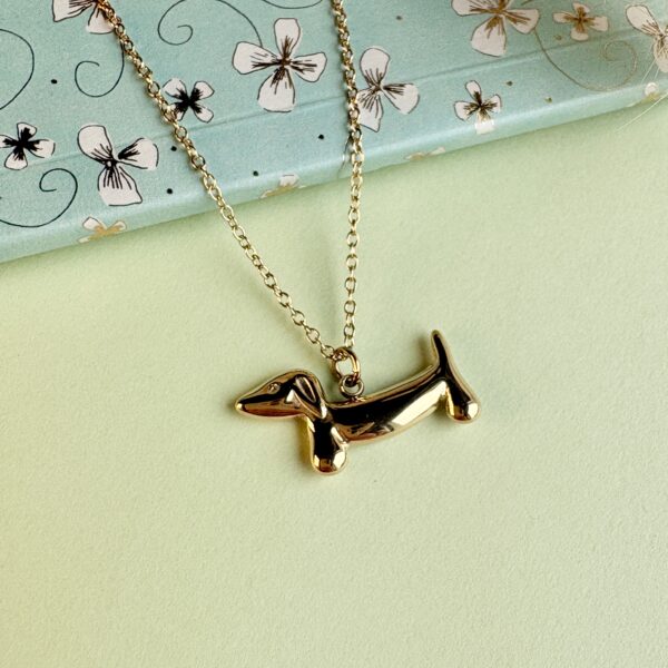 Collier teckel doré posé sur fond fleuri turquoise